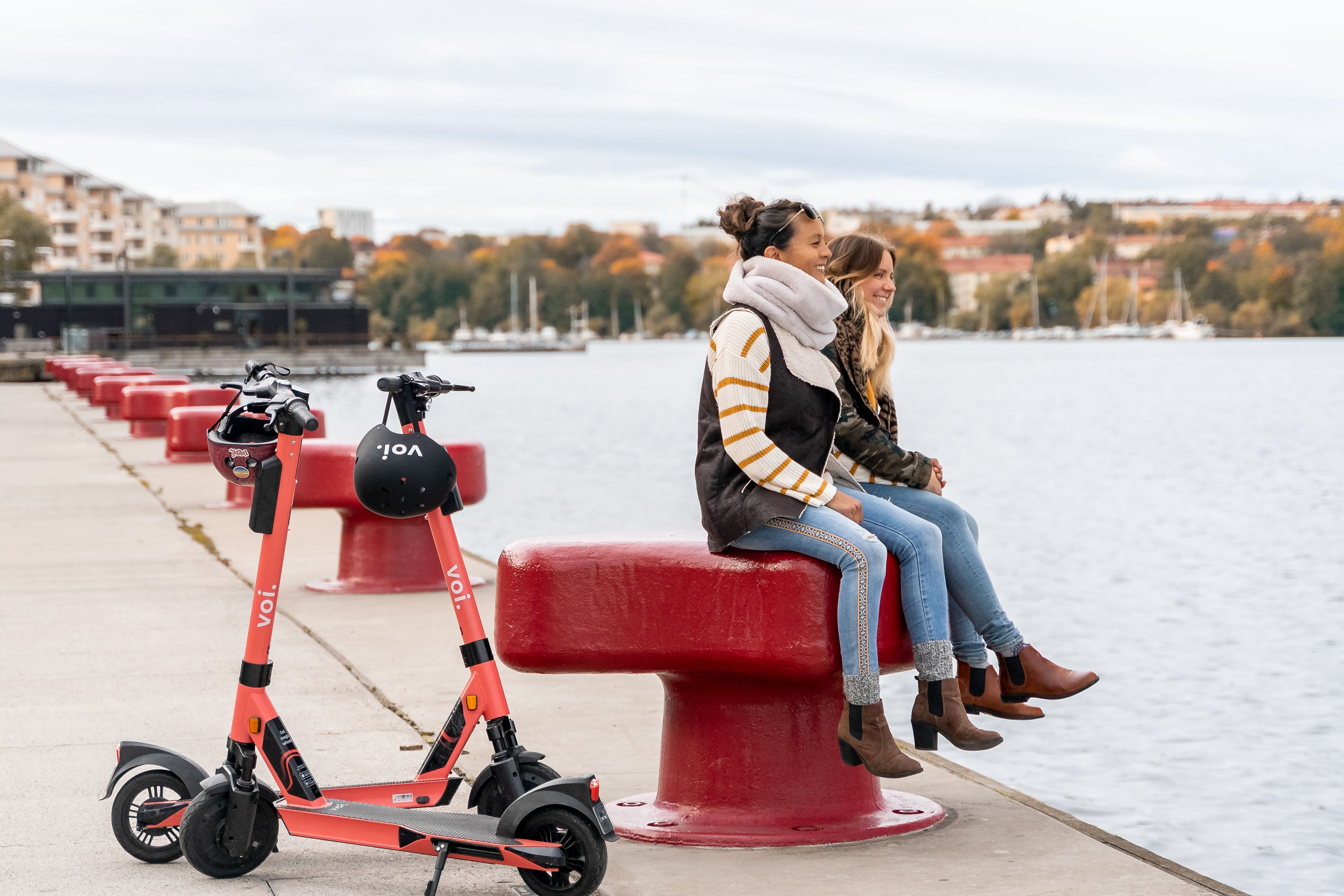 Two friends using Voi e-scooters